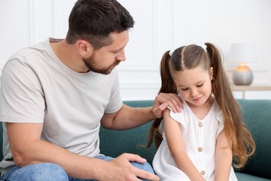 Photo of Father supporting his sad daughter on sofa at home