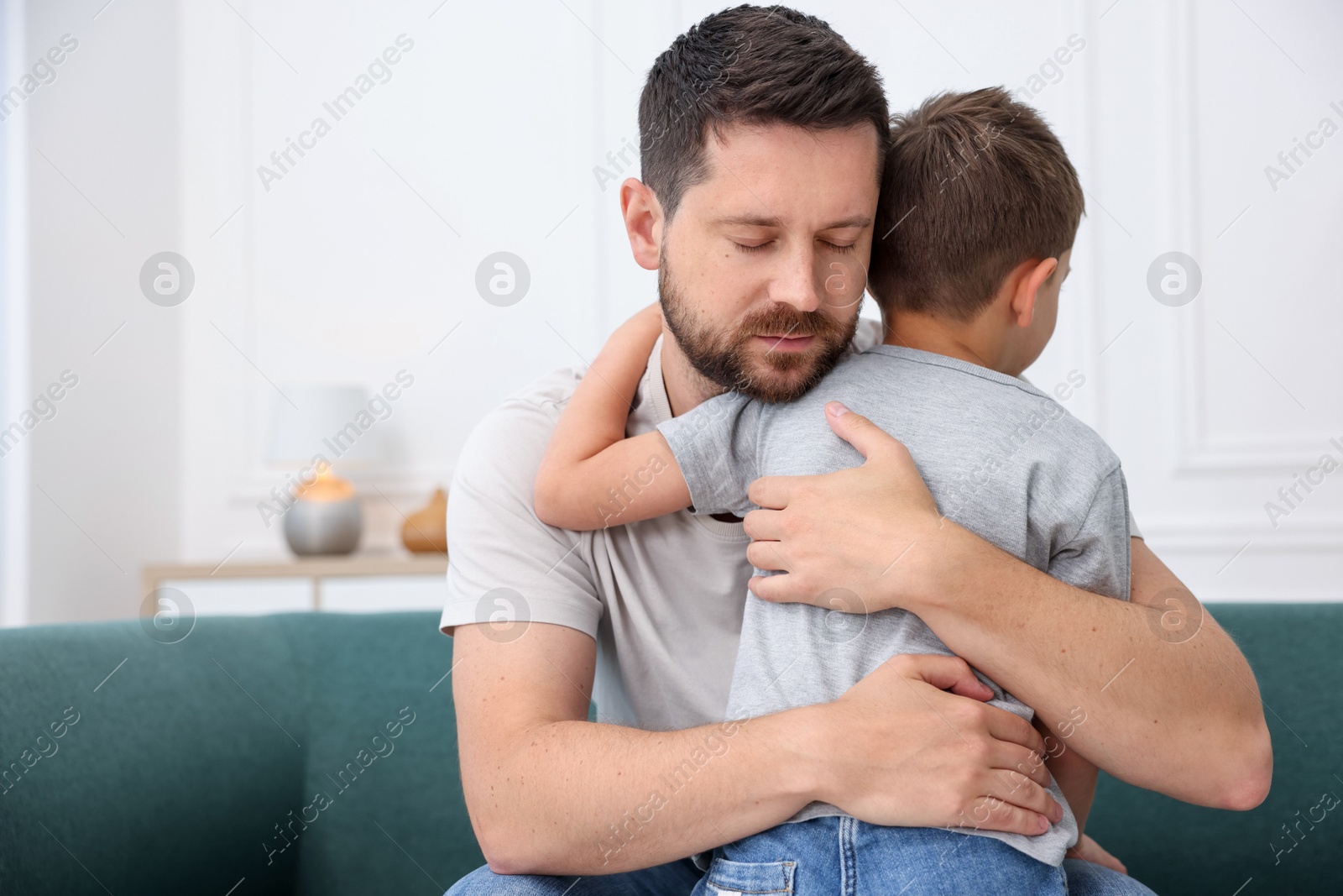 Father supporting his sad son on sofa at home Photo of Father supporting his sad son on sofa at home