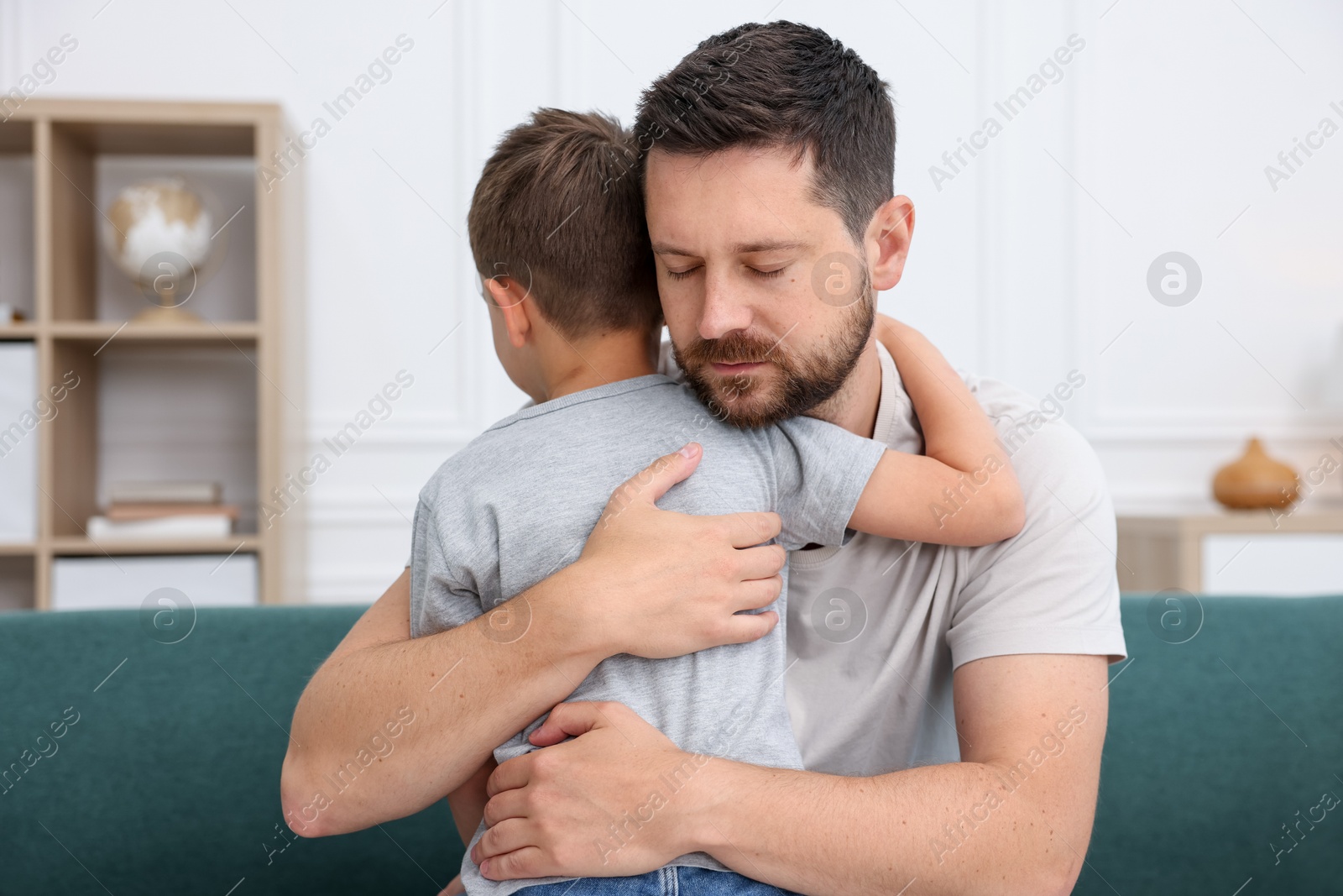 Father supporting his sad son on sofa at home Photo of Father supporting his sad son on sofa at home