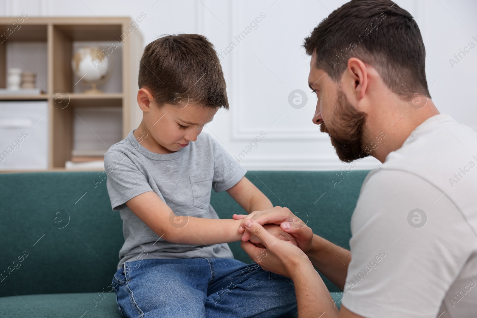 Father supporting his sad son on sofa at home Photo of Father supporting his sad son on sofa at home