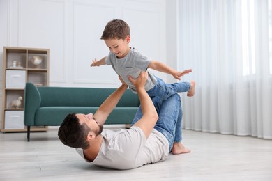 Photo of Father and his son spending time together on warm floor at home. Heating system