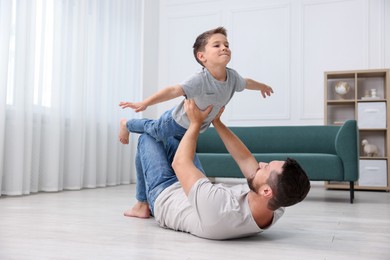 Photo of Father and his son spending time together on warm floor at home. Heating system