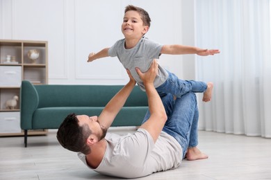Photo of Father and his son spending time together on warm floor at home. Heating system