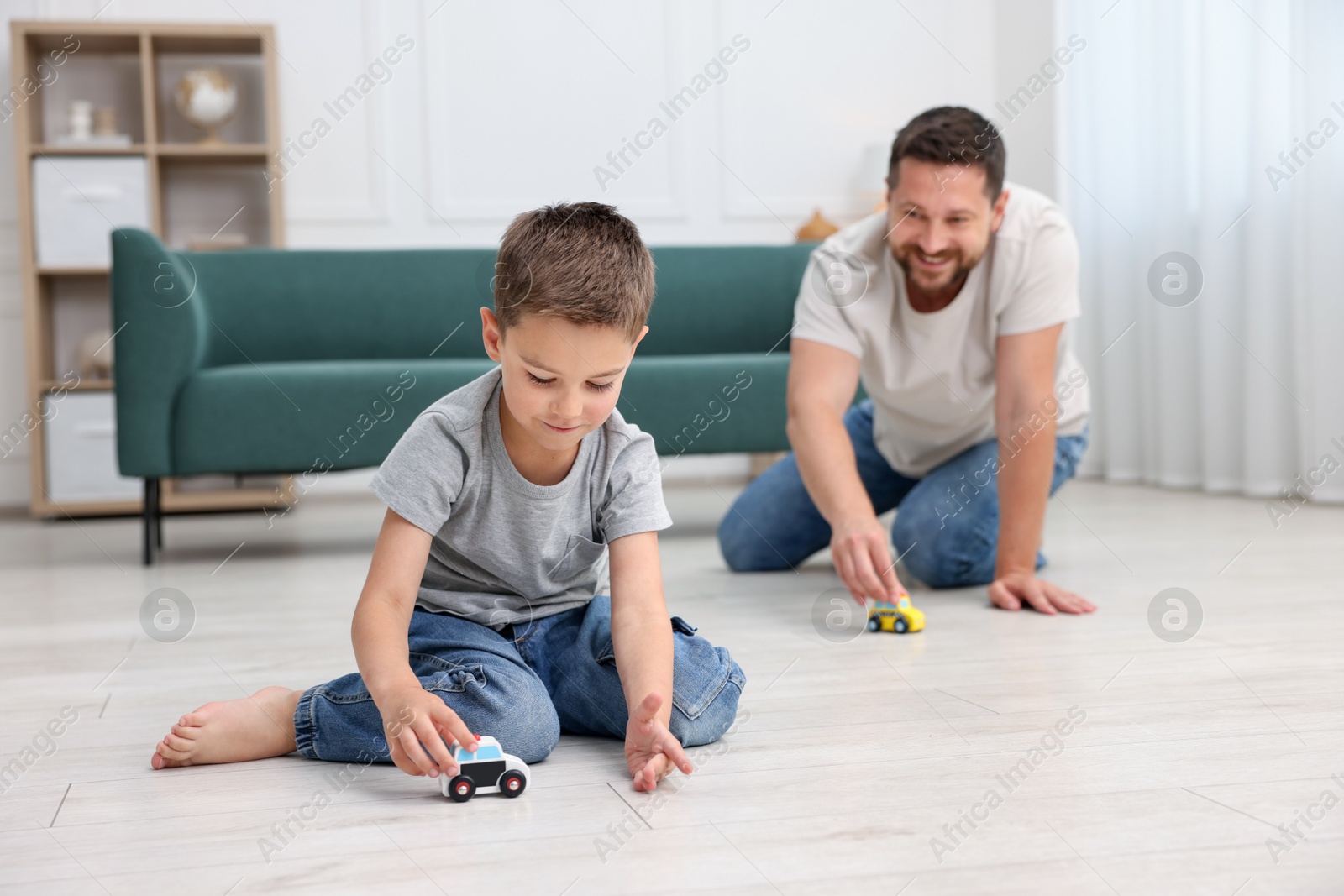Father and his son playing with toys on warm floor at home, selective focus. Heating system Photo of Father and his son playing with toys on warm floor at home, selective focus. Heating system
