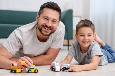 Photo of Father and his son playing with toys on warm floor at home. Heating system