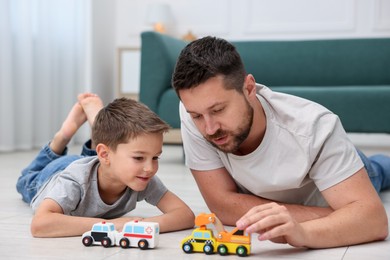 Photo of Father and his son playing with toys on warm floor at home. Heating system