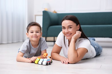 Photo of Mother and her son playing with toys on warm floor at home. Heating system