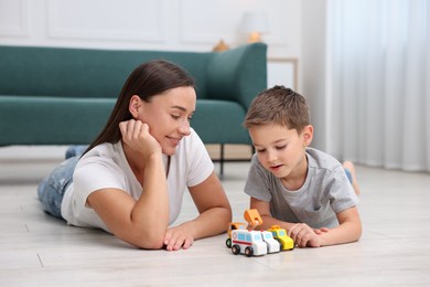 Photo of Mother and her son playing with toys on warm floor at home. Heating system