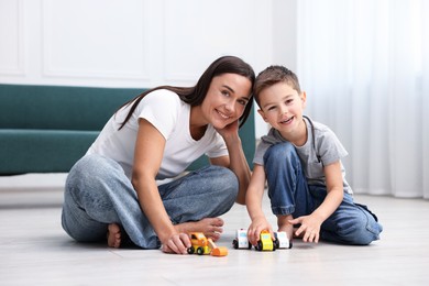 Photo of Mother and her son playing with toys on warm floor at home. Heating system