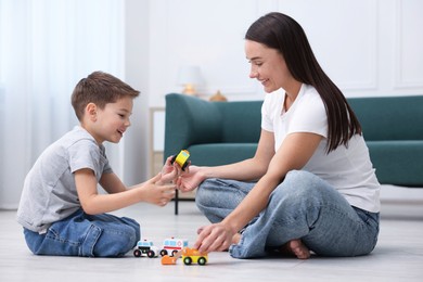 Photo of Mother and her son playing with toys on warm floor at home. Heating system