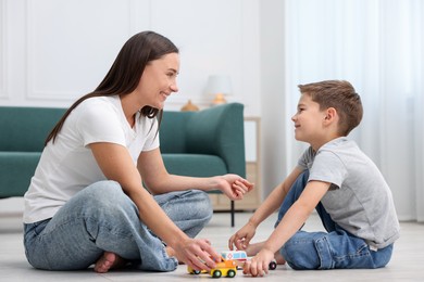 Photo of Mother and her son playing with toys on warm floor at home. Heating system
