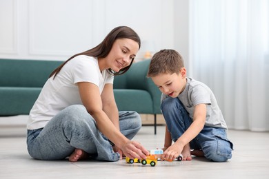 Photo of Mother and her son playing with toys on warm floor at home. Heating system