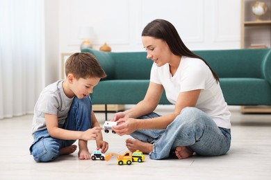 Photo of Mother and her son playing with toys on warm floor at home. Heating system