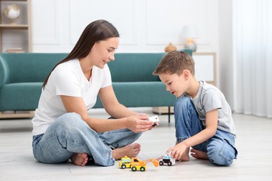 Photo of Mother and her son playing with toys on warm floor at home. Heating system