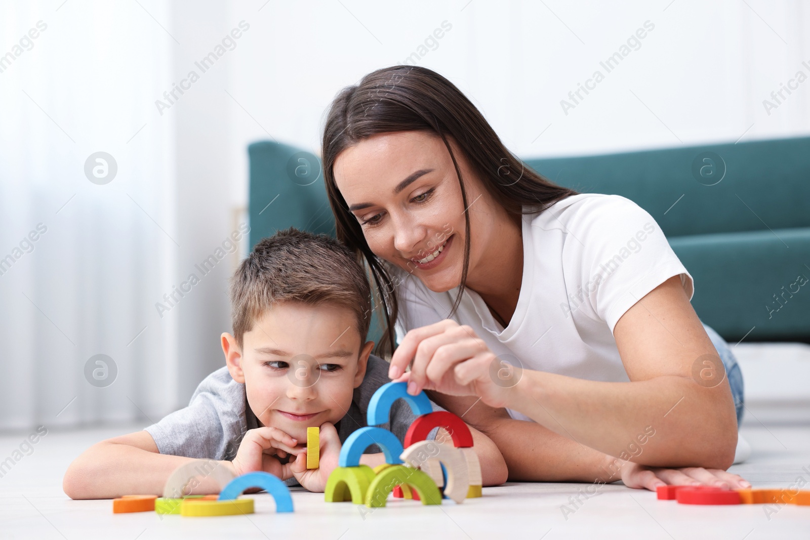 Mother and her son playing with toys on warm floor at home. Heating system Photo of Mother and her son playing with toys on warm floor at home. Heating system