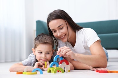 Photo of Mother and her son playing with toys on warm floor at home. Heating system