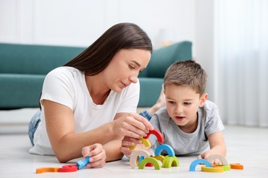 Photo of Mother and her son playing with toys on warm floor at home. Heating system