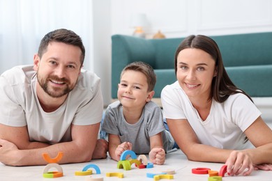 Photo of Parents and their son playing with toys on warm floor at home. Heating system