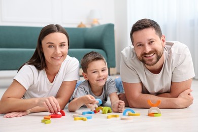 Photo of Parents and their son playing with toys on warm floor at home. Heating system