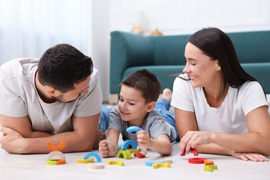 Photo of Parents and their son playing with toys on warm floor at home. Heating system