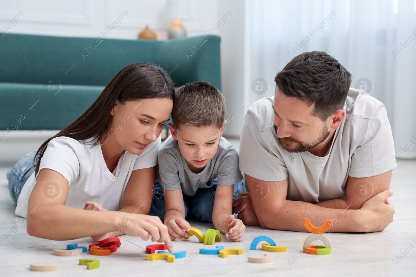 Parents and their son playing with toys on warm floor at home. Heating system Photo of Parents and their son playing with toys on warm floor at home. Heating system