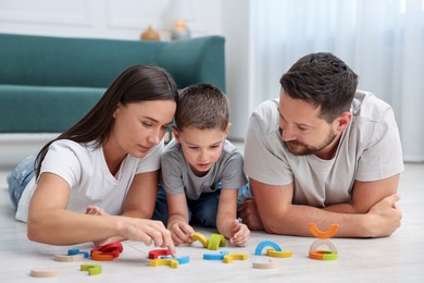Photo of Parents and their son playing with toys on warm floor at home. Heating system