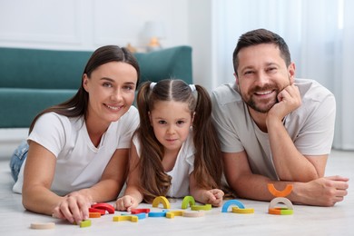 Photo of Parents and their daughter playing with toys on warm floor at home. Heating system