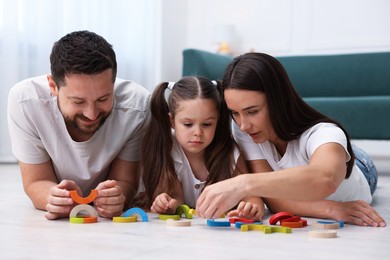 Photo of Parents and their daughter playing with toys on warm floor at home. Heating system