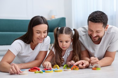 Photo of Parents and their daughter playing with toys on warm floor at home. Heating system