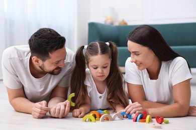 Photo of Parents and their daughter playing with toys on warm floor at home. Heating system