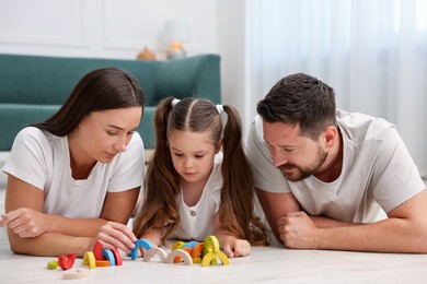 Photo of Parents and their daughter playing with toys on warm floor at home. Heating system