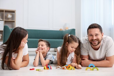 Photo of Parents and their kids playing with toys on warm floor at home. Heating system