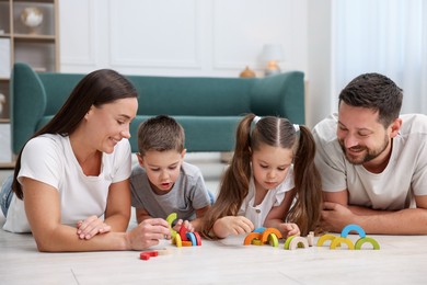 Photo of Parents and their kids playing with toys on warm floor at home. Heating system