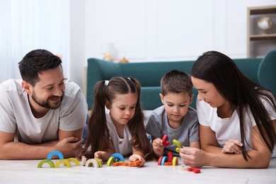 Photo of Parents and their kids playing with toys on warm floor at home. Heating system