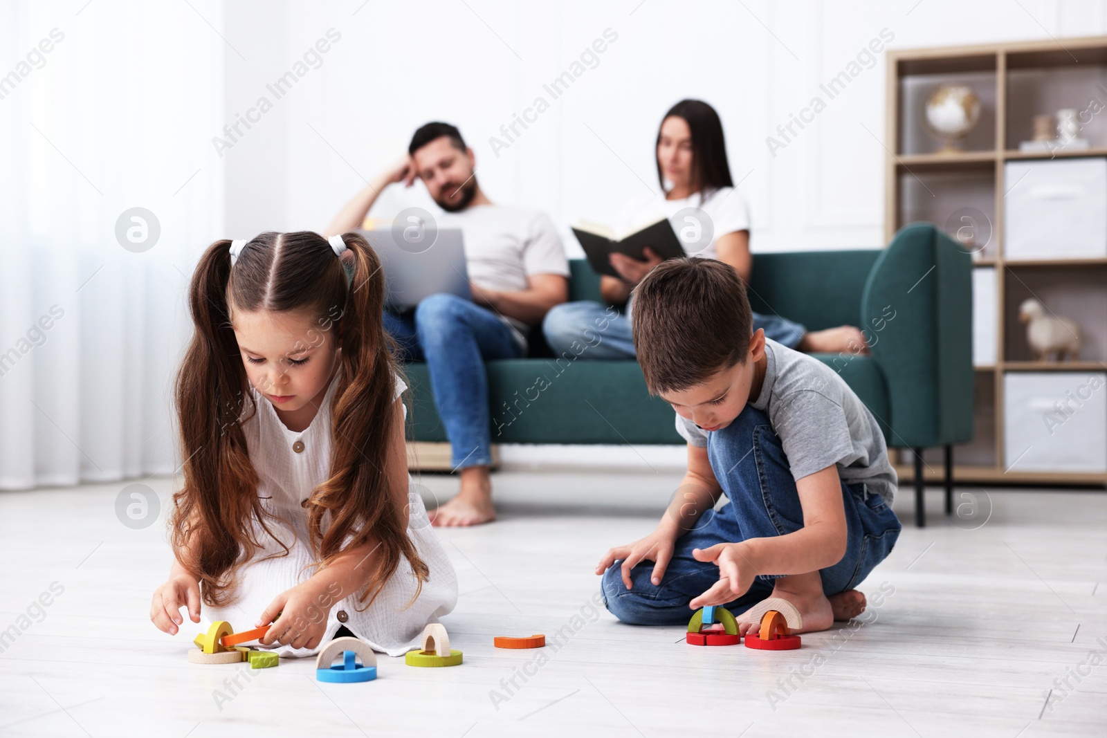 Kids playing with toys near their parents on warm floor at home, selective focus. Heating system Photo of Kids playing with toys near their parents on warm floor at home, selective focus. Heating system