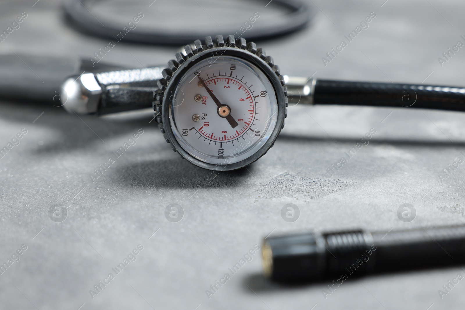 Photo of One tire inflation gun with gauge on grey background, closeup