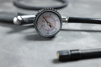 Photo of One tire inflation gun with gauge on grey background, closeup