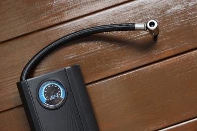 Photo of One tire inflator on wooden background, closeup