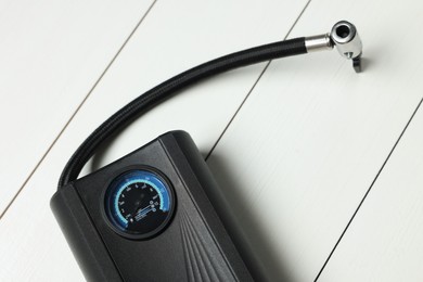 Photo of One modern tire inflator on white wooden background, closeup