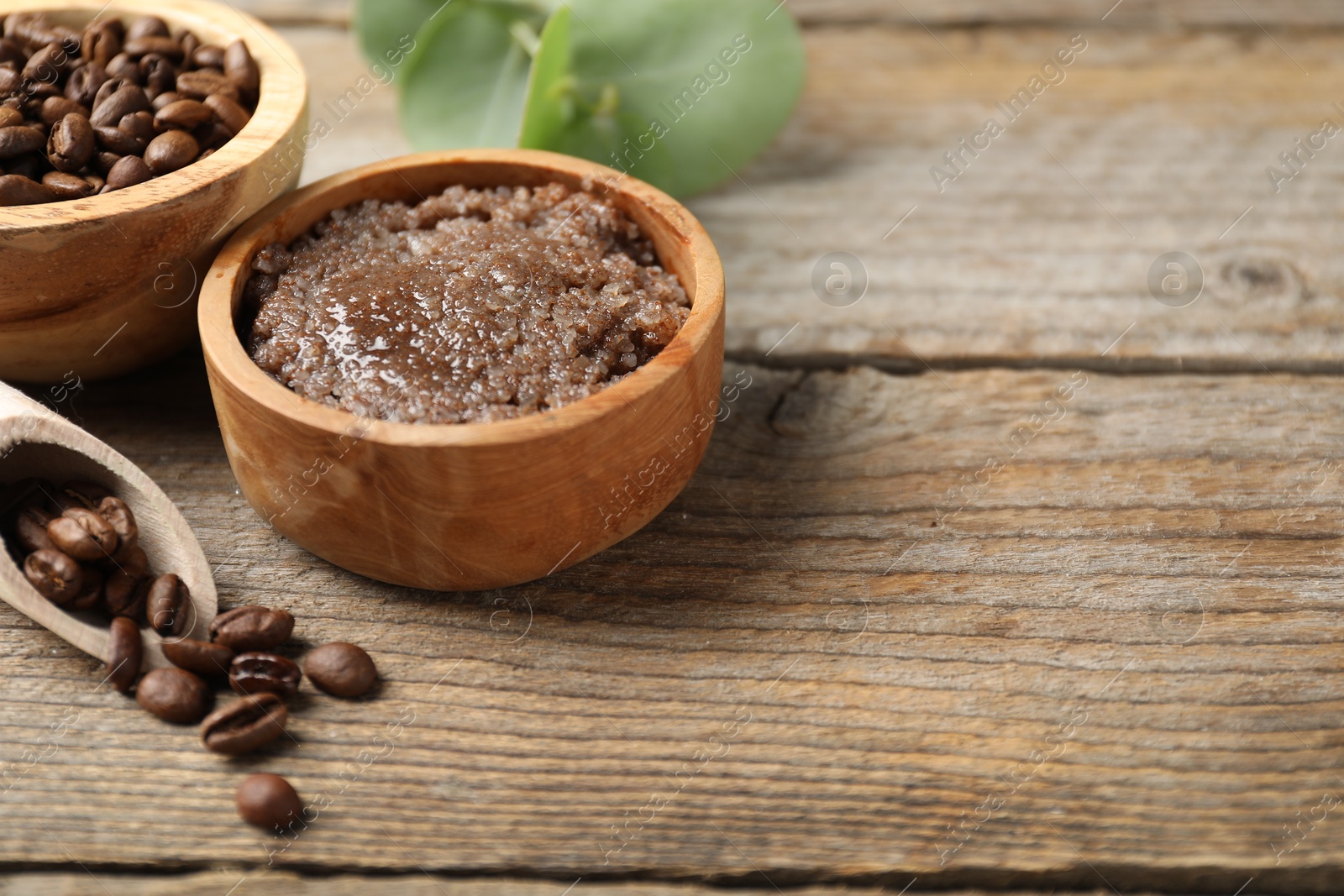 Photo of Natural body scrub and coffee beans on wooden table, closeup. Space for text