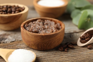 Photo of Natural body scrub and coffee beans on wooden table, closeup
