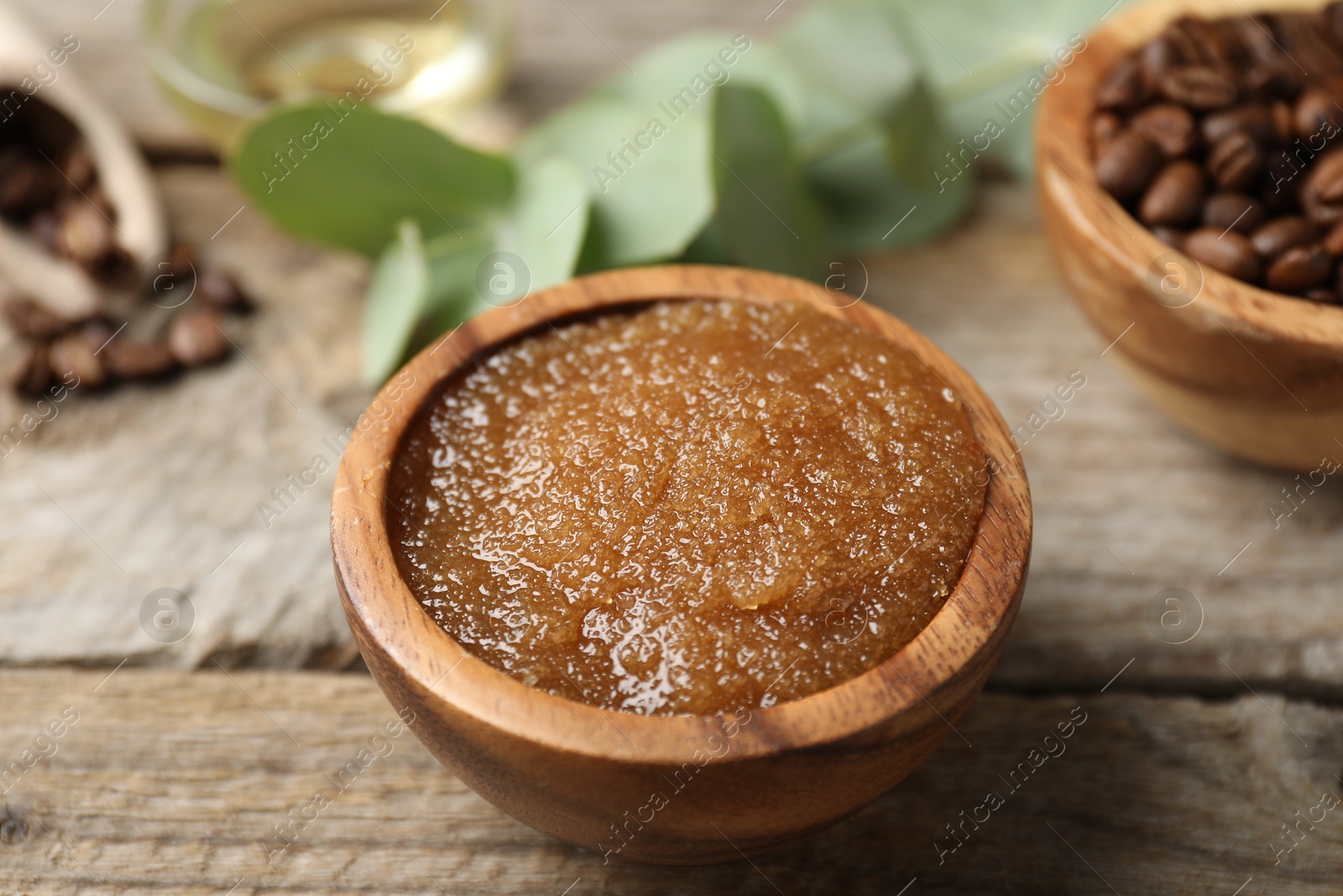 Photo of Natural body scrub and coffee beans on wooden table, closeup