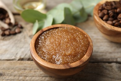 Photo of Natural body scrub and coffee beans on wooden table, closeup