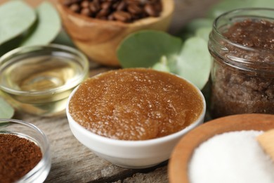 Photo of Natural body scrub and ingredients on wooden table, closeup