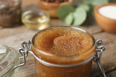 Photo of Natural body scrub and ingredients on wooden table, closeup