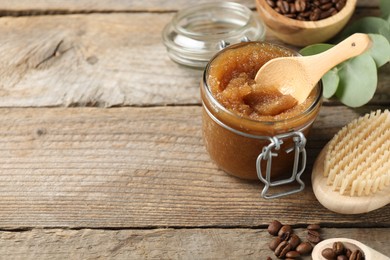 Photo of Natural body scrub and coffee beans on wooden table, closeup. Space for text