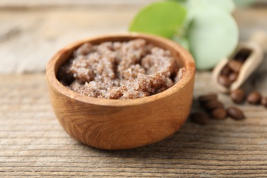 Photo of Natural body scrub and coffee beans on wooden table, closeup