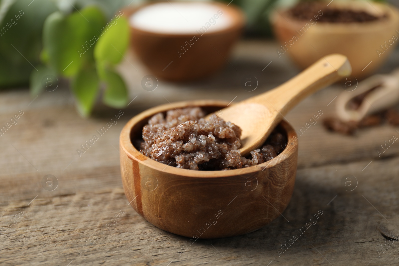 Photo of Natural body scrub and ingredients on wooden table, closeup