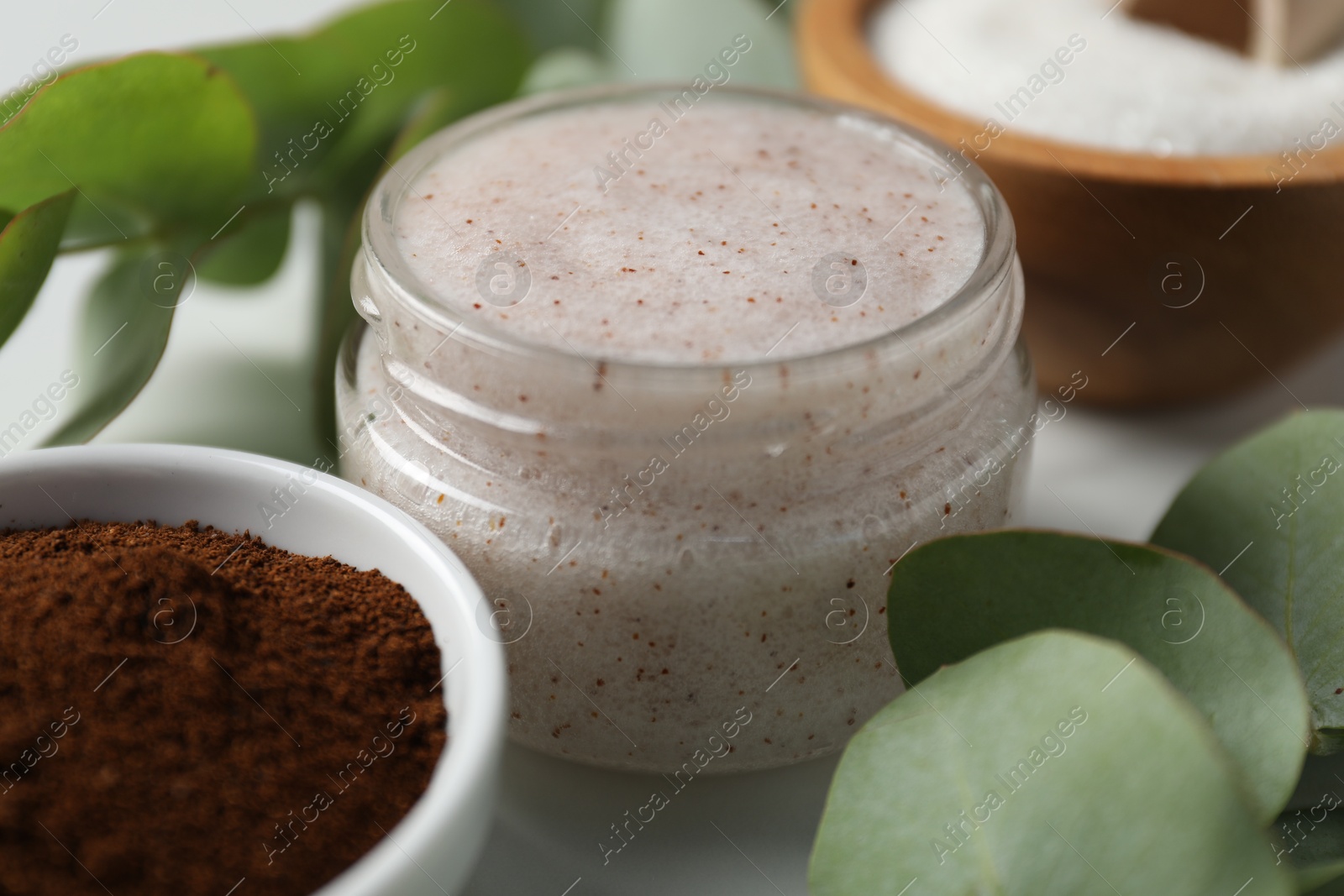 Photo of Natural body scrub and ingredients on white table, closeup