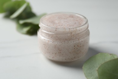 Photo of Natural body scrub and eucalyptus on white table, closeup